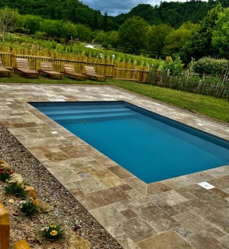 - une piscine bleue dans une cour avec des chaises dans l'établissement Esparoutis Chambres d'hôtes du Charme, à Saint-Cybranet