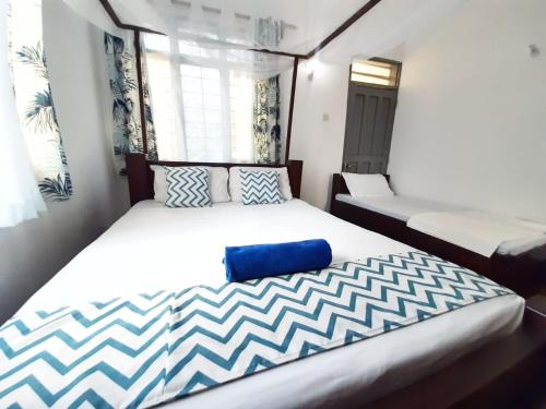 a bedroom with a large bed with blue and white sheets at Cycad Palm Diani in Diani Beach
