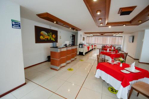 a restaurant with red tables and chairs and a counter at Hotel Cuellars in Pasto