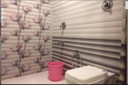 a bathroom with a pink toilet and flowers on the wall at HOTEL AVISHA Residency in Marmagao