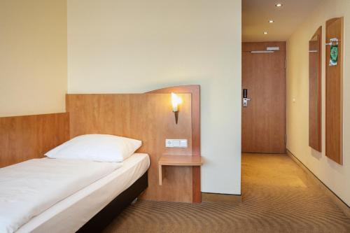 a hotel room with a bed and a hallway at ACHAT Hotel Braunschweig in Braunschweig