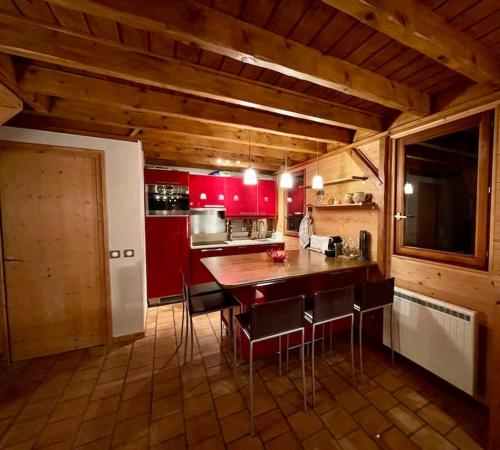 cocina con armarios rojos, mesa y sillas en Le Roc - Courchevel Village, en Courchevel