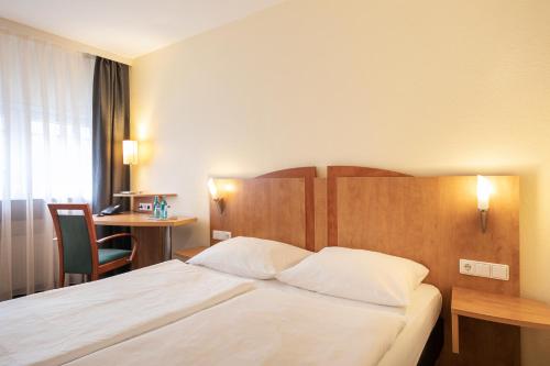 a hotel room with a bed and a desk at ACHAT Hotel Braunschweig in Braunschweig
