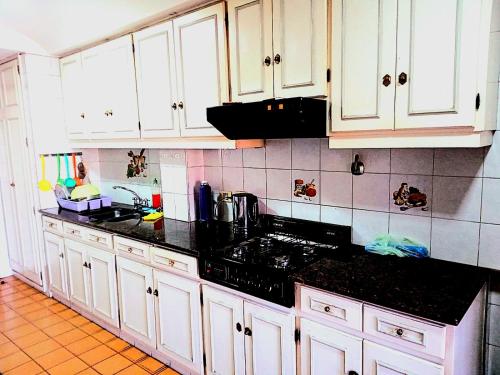una cocina con armarios blancos y encimeras negras en Casa Bravo en Mendoza