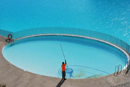 a man is standing in front of a swimming pool at Papudo Laguna Un Lugar Privilegiado in Papudo