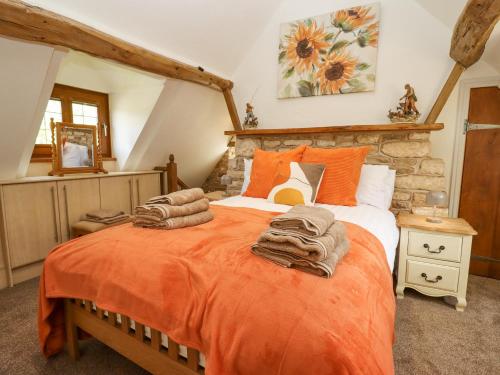 a bedroom with a large bed with an orange blanket at Manor Farm in Cheltenham