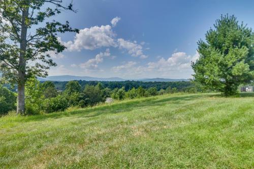 a field of grass with trees and mountains in the background at Rustic Baileys Retreat Cabin Near Wineries! in Crozet