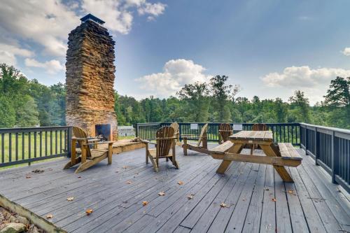 a deck with picnic tables and a stone chimney at Charlottesville Getaway in Baileys Retreat! in Crozet