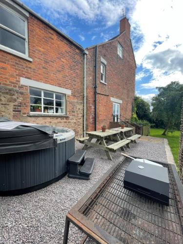 a patio with a table and a picnic table and a building at Cosy Farm house in Forest of Dean in Westbury on Severn