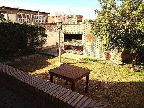 un banco de madera en un patio con chimenea de ladrillo en Casa Bravo en Mendoza