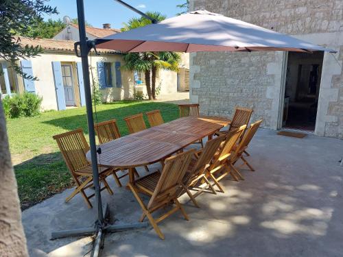 a wooden table and chairs under an umbrella at Maison pour 6 personnes avec piscine et proche de la plage in Aytré