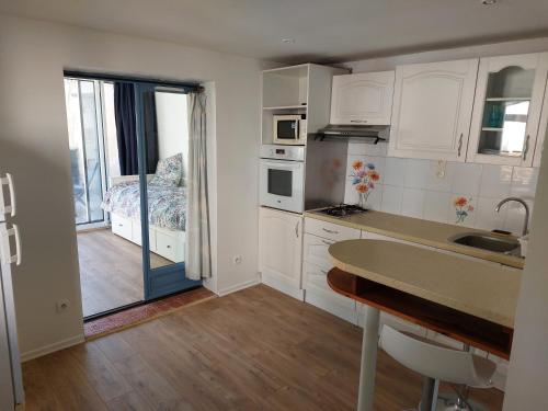 a kitchen with white cabinets and a table with a sink at Maison pour 6 personnes avec piscine et proche de la plage in Aytré