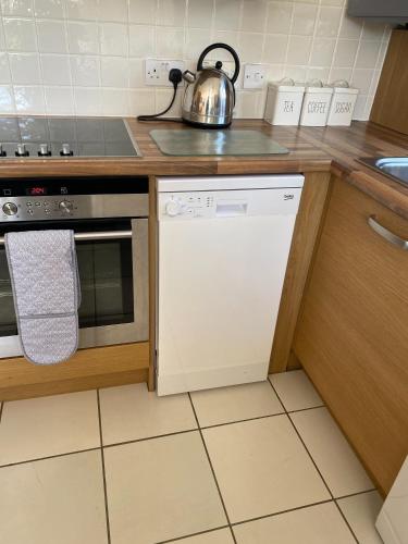 a kitchen with a dishwasher and a tea kettle at River Penthouse Little Paxton - 75 Skipper Way in Saint Neots