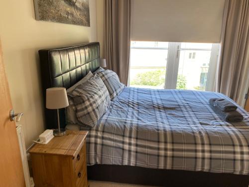 a bedroom with a bed with a blue blanket and a window at River Penthouse Little Paxton - 75 Skipper Way in Saint Neots