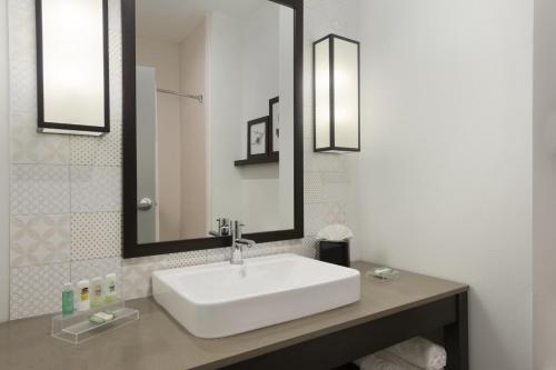 y baño con lavabo blanco y espejo. en Country Inn & Suites by Radisson, Enid, OK, en Enid