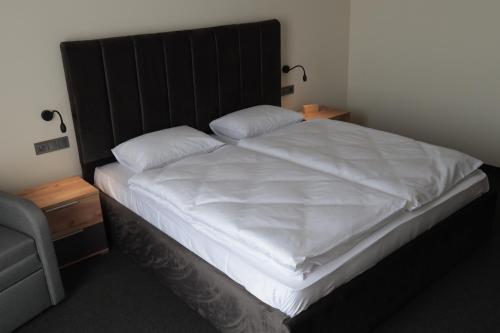 a bedroom with a large white bed with a wooden headboard at Готель Карпатія in Mukacheve