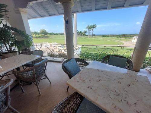 a patio with tables and chairs and a view of a golf course at Coconut Grove 8 Luxury Villa by Island Villas in Saint James