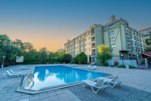 a swimming pool with two chairs and a building at Anemon Kent Ege Otel in Burunabat