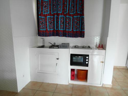 a small white kitchen with a microwave and a window at Appartement confortable à Grand Popo, 50 m², piscine partagée in Grand-Popo