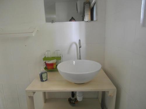 La salle de bains est pourvue d'un lavabo blanc sur une table en bois. dans l'établissement Appartement d'une chambre a Grand Popo a 10 m de la plage avec piscine partagee jardin clos et wifi, à Grand-Popo