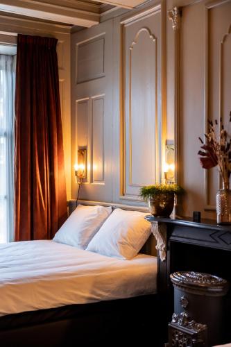 a bedroom with a bed with white sheets and a window at De Olde Signorie in Leeuwarden