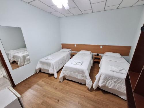 a room with four beds and a mirror at Hotel Itapema in Valinhos