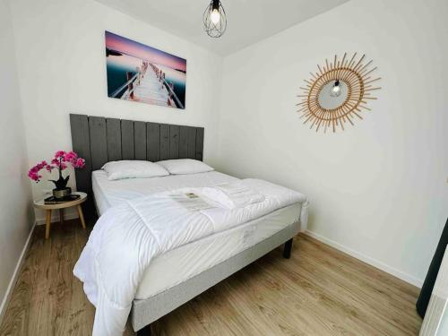 Schlafzimmer mit einem Bett mit weißer Bettwäsche und einem Spiegel in der Unterkunft Le cocon - 2 km de la plage in Saint-Vivien