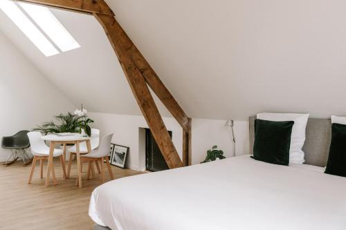 a bedroom with a white bed and a table and chairs at BnB Manere in Grimbergen