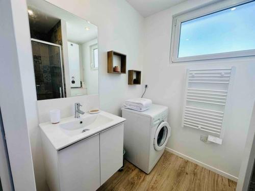 ein weißes Badezimmer mit einer Waschmaschine und einem Waschbecken in der Unterkunft Le cocon - 2 km de la plage in Saint-Vivien