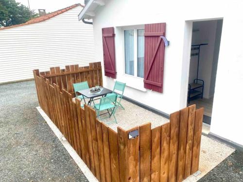 eine Terrasse mit einem Tisch und Stühlen neben einem Zaun in der Unterkunft Le cocon - 2 km de la plage in Saint-Vivien