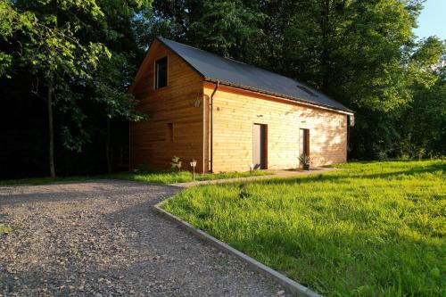 a wooden barn sitting in the grass next to a road at Apartamenty Domek na Roztoczu in Horyniec Zdrój