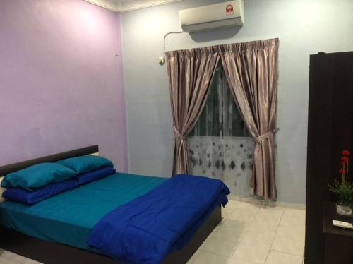 a bedroom with a blue bed and a window at KJ Homestay Balok Kuantan in Kampong Chengal Lempong