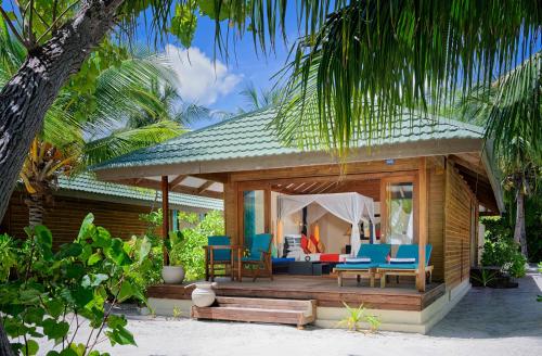 een resort met een terras met stoelen en een bed bij Canareef Resort Maldives in Meedhoo