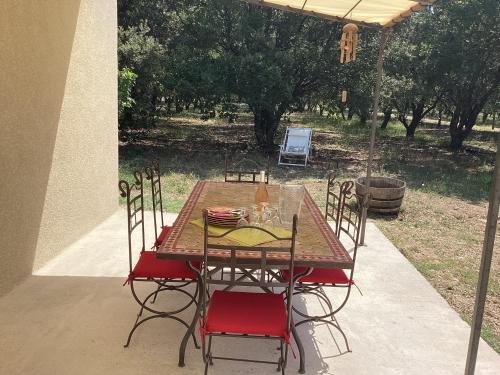 une table et des chaises en bois dans une cour dans l'établissement Au mas des Chênes, à La Baume-de-Transit