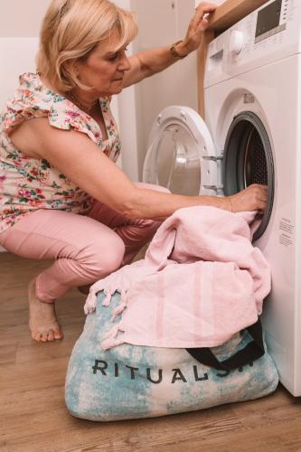 a woman is loading a clothes into a washing machine at Holiday Home Relax in Ypres