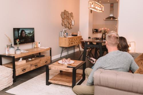 mężczyzna i kobieta siedzący w salonie oglądający telewizję w obiekcie Holiday Home Relax w mieście Ypres