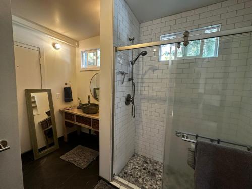 La salle de bains est pourvue d'une douche, d'un lavabo et d'un miroir. dans l'établissement Guest House - V-land, à Haleiwa