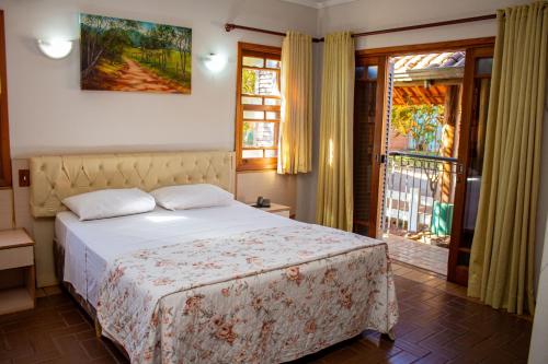 1 dormitorio con 1 cama y puerta a un balcón en Hotel Fazenda Poços de Caldas, en Poços de Caldas