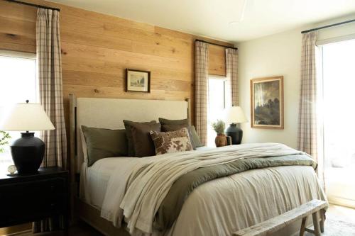 a bedroom with a large bed with wooden walls at NEW Creek Side, Luxury Cabin – Willow Creek in Stephens Gap