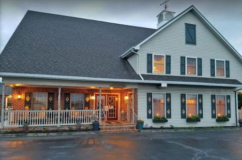 a white house with a porch with orange doors at Country Living Inn in Lancaster