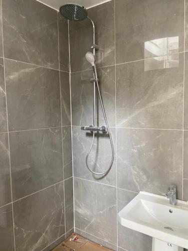 a shower with a shower head and a sink in a bathroom at Aux Terrasses de la Lune in Paris