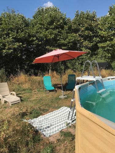 a pool with chairs and an umbrella and a table and chairs at Gite de Folgoux in Malvières