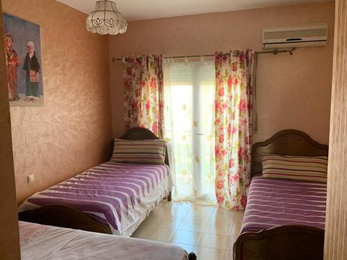 um quarto com 2 camas e uma janela com cortinas em Ap6 em Saïdia
