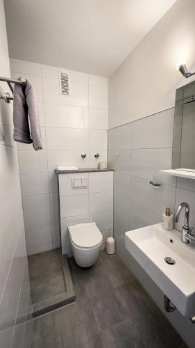 a white bathroom with a toilet and a sink at Hotel Schmidt garni in Essen