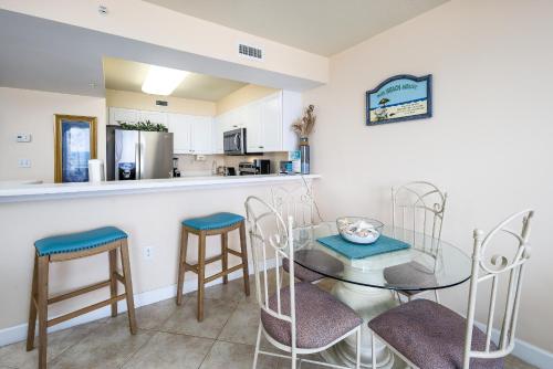 een keuken en eetkamer met een glazen tafel en stoelen bij Pelican Isle 412: Have a splashing good time at the beach in this CONDO in Fort Walton Beach