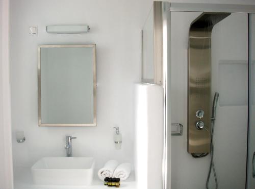 a bathroom with a sink and a mirror and a shower at Blugreen Stegna Suites and Apartments in Archangelos