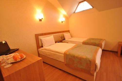 a room with two beds and a table with a laptop at Grand Anzac Hotel in Çanakkale