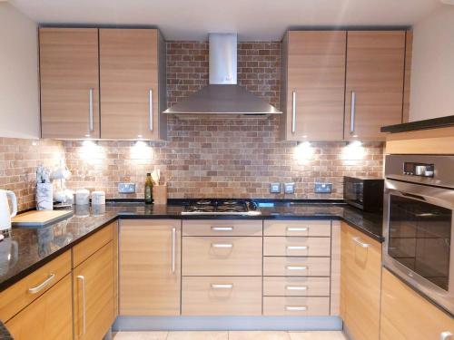 a kitchen with wooden cabinets and a brick wall at Seafront Holiday Home in Southend-on-Sea