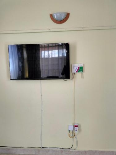 KAJIADOHOMES في Kajiado: تلفزيون على جدار بقطة جالسة تحت النافذة