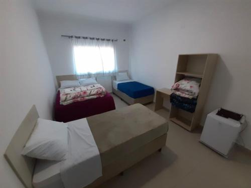 a small bedroom with two beds and a window at Pousada Gabriel in São Miguel Arcanjo